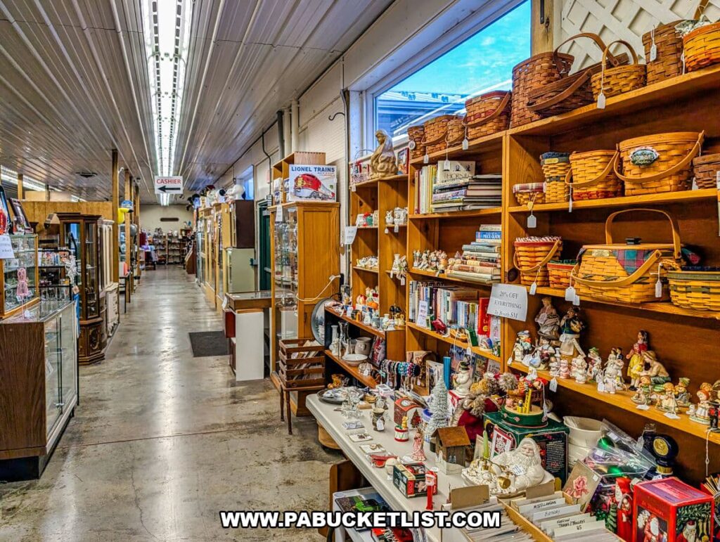 Wide interior aisle at Morning Sun Marketplace in York County, PA, lined with vendor booths displaying antiques, Longaberger baskets, books, figurines, glass cases, and collectibles under bright overhead lighting.
