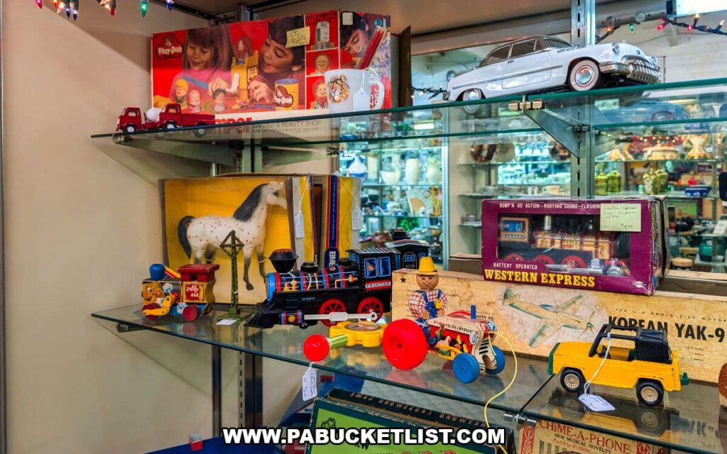 Glass display shelves at Zelma’s Emporium filled with vintage toys, including tin trains, toy vehicles, boxed playsets, and classic childhood collectibles showcased inside the two-story antique mall in Adams County, Pennsylvania.