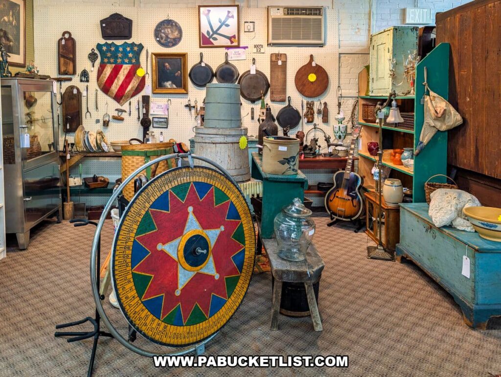 Eclectic antique booth at Zelma’s Emporium featuring a large painted game wheel, vintage cast iron skillets, Americana wall art, wooden crocks, early furniture, and a vintage acoustic guitar displayed inside the two-story antique mall in Adams County, Pennsylvania.