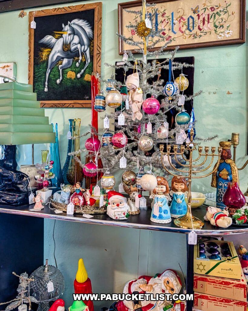 Mid-century modern tabletop display inside American Daydream Antiques in York County, Pennsylvania, featuring vintage aluminum Christmas trees, retro lamps, colorful glassware, holiday tins, and eclectic home decor arranged within a multi-vendor antique shop