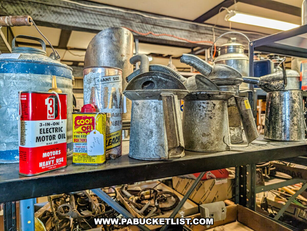 A shelf of vintage hardware and industrial items at Black Shutter Antiques in New Oxford, Pennsylvania, including metal oil cans, oilers, lubricant tins, and workshop tools displayed inside the multi-vendor antique store