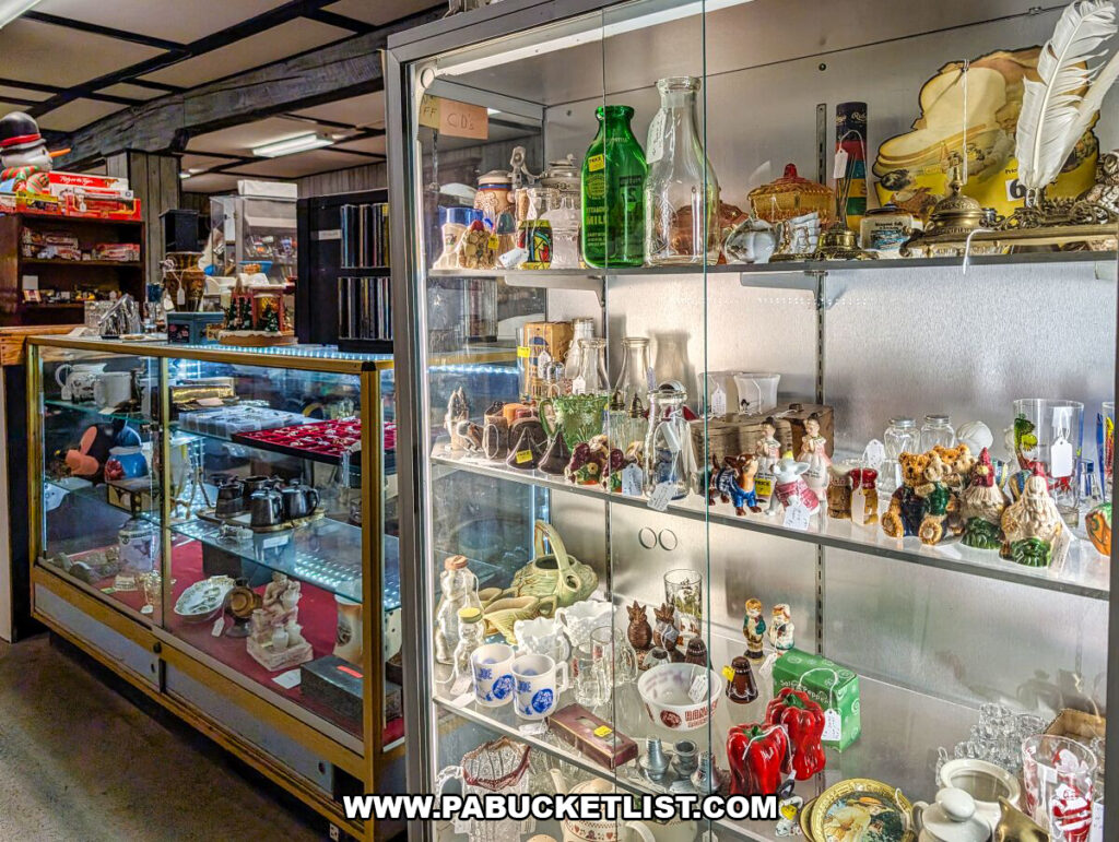 Glass display cases at Black Shutter Antiques in New Oxford, Pennsylvania, showcasing vintage bottles, milk bottles, figurines, small collectibles, and decorative items arranged inside the multi-vendor antique store