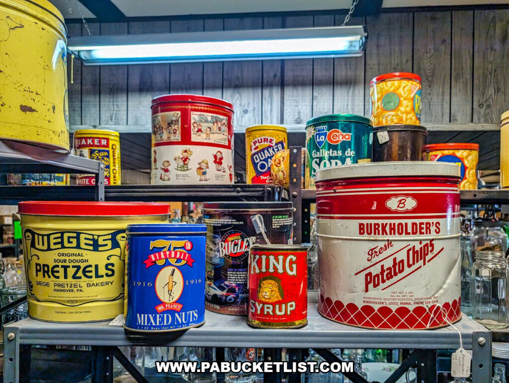 A shelf at Black Shutter Antiques in New Oxford, Pennsylvania, displaying vintage advertising tins including pretzels, mixed nuts, potato chips, syrup, and cookie containers inside the multi-vendor antique store