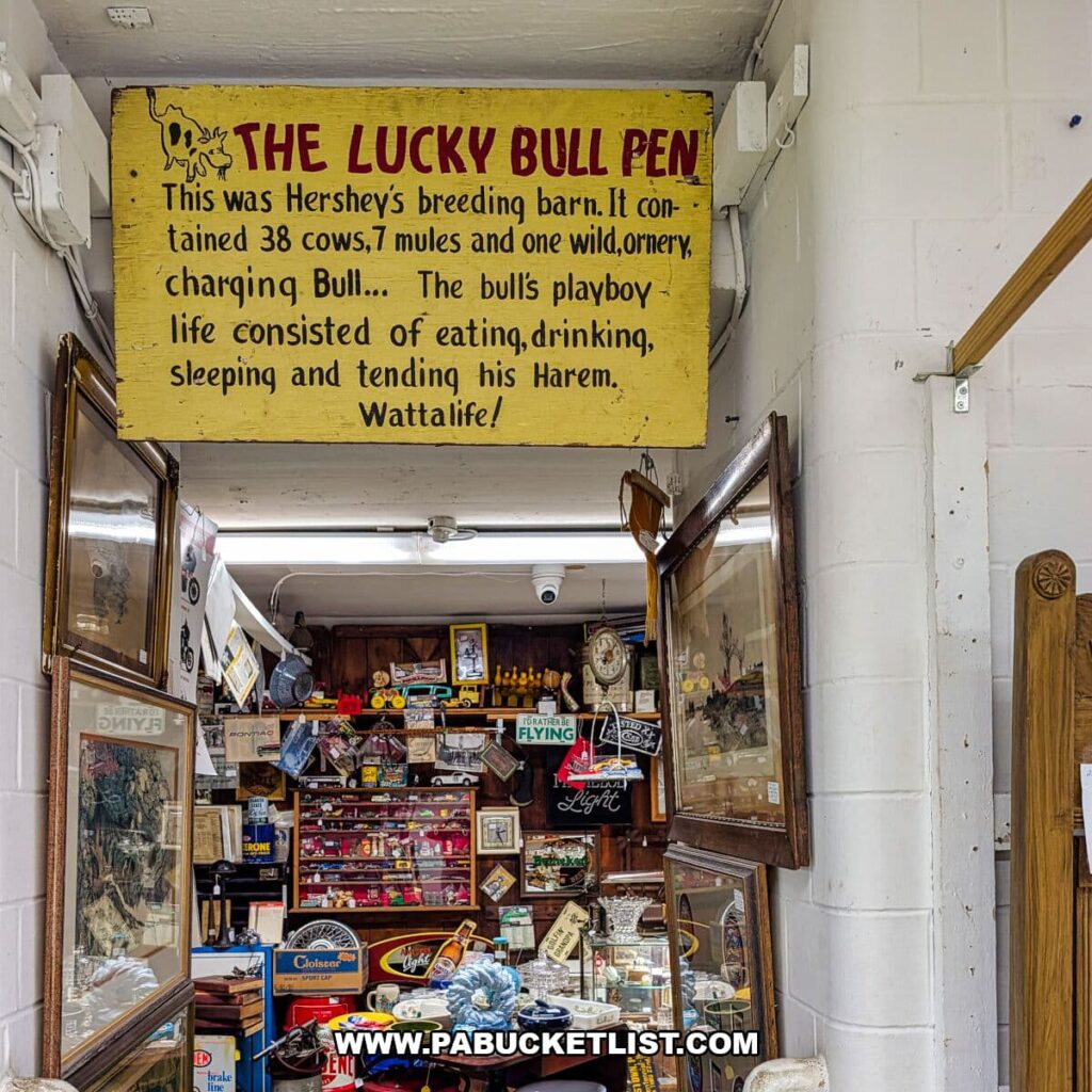 Interior passageway at Crossroads Antique Mall in Hershey, Pennsylvania, featuring a vintage yellow sign titled “The Lucky Bull Pen” describing Hershey’s former breeding barn, with surrounding vendor displays of antique advertising, framed prints, tools, and nostalgic collectibles.