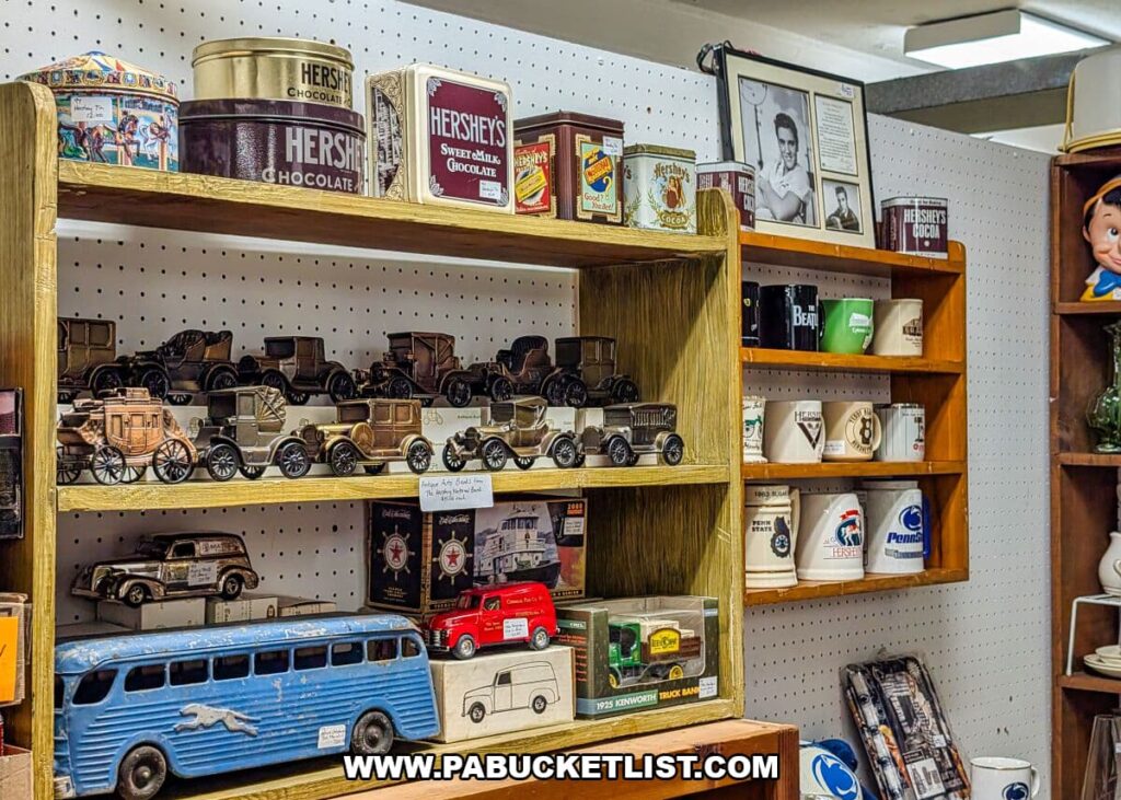 Vendor display at Crossroads Antique Mall in Hershey, Pennsylvania, featuring vintage Hershey’s chocolate tins, collectible mugs, model vehicles, toy cars, buses, and local memorabilia arranged on wooden shelves inside the historic barn.
