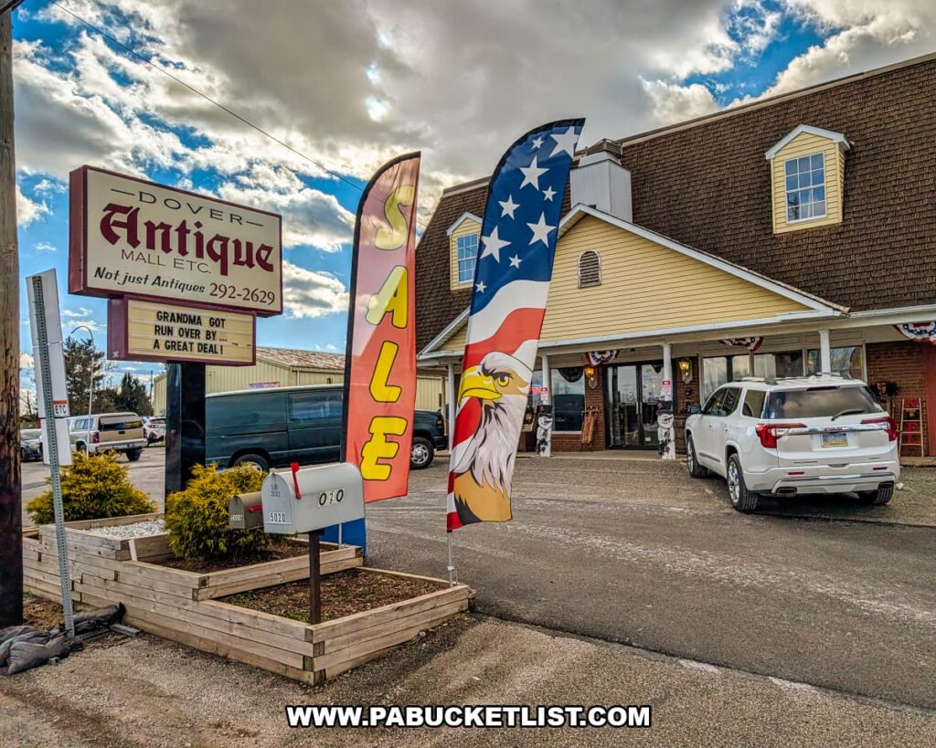 Exterior view of Dover Antique Mall in York County, Pennsylvania, showing the roadside sign, colorful sale flags, and the large two-story building with parked vehicles out front, highlighting the welcoming entrance to a multi-vendor antique mall.