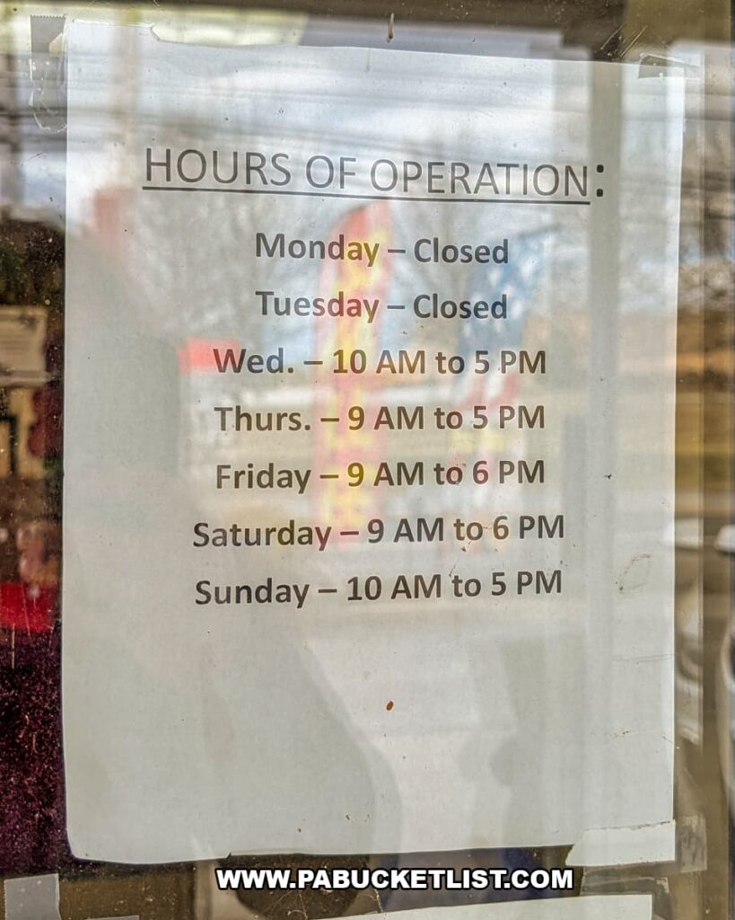 Close-up of a printed hours of operation sign posted at Dover Antique Mall in York County, Pennsylvania, listing opening and closing times for each day of the week on the glass door of the multi-vendor antique mall.