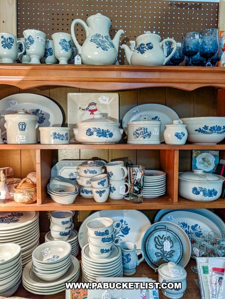 Shelving display inside Dover Antique Mall in York County, Pennsylvania, filled with matching vintage Pfaltzgraff stoneware dishes featuring blue floral patterns, including plates, bowls, mugs, serving dishes, and teapots neatly arranged on wooden shelves.