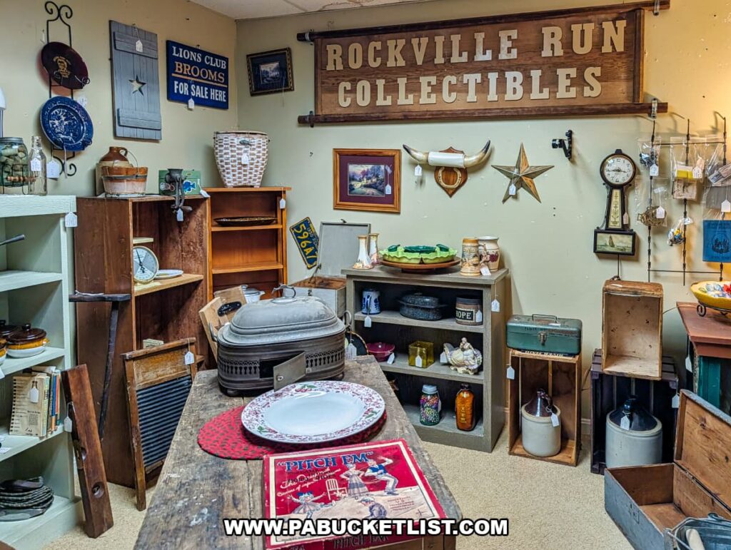 Interior view of a vendor booth at Dover Antique Mall in York County, Pennsylvania, featuring rustic wooden furniture, vintage crocks, washboards, tinware, framed signs, kitchenware, and farmhouse-style décor arranged throughout the display.