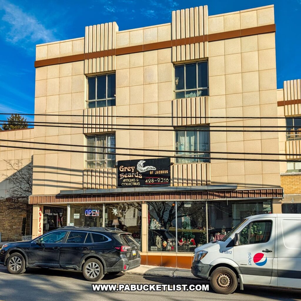 Exterior view of Grey Beards Antiques in York County, Pennsylvania, showing the four-story Art Deco-style building in Jacobus with large display windows, storefront signage, and parked vehicles along the street.