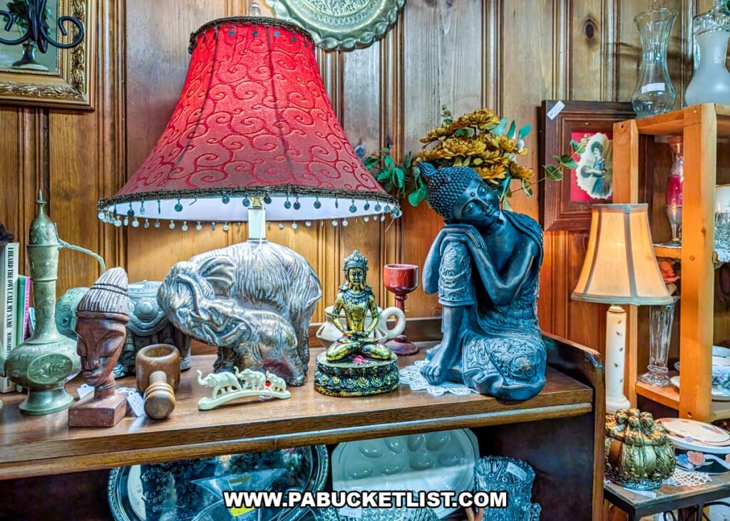 Vintage lamps, figurines, and decorative art displayed on a wooden shelf at Grey Beards Antiques in York County, Pennsylvania, featuring ornate table lamps, Buddha statues, animal sculptures, and glassware inside the multi-vendor antique mall in Jacobus.