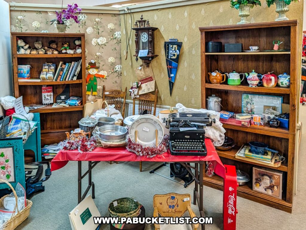Vintage typewriter, kitchenware, clocks, books, and decorative collectibles displayed on tables and wooden shelves inside Grey Beards Antiques in York County, Pennsylvania, highlighting a curated vendor booth within the multi-vendor antique mall in Jacobus.