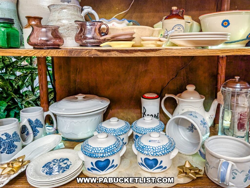 Assorted vintage kitchenware displayed on wooden shelves at Grey Beards Antiques in York County, Pennsylvania, featuring ceramic bowls, teapots, mugs, plates, glassware, and patterned stoneware inside the multi-vendor antique mall in Jacobus.
