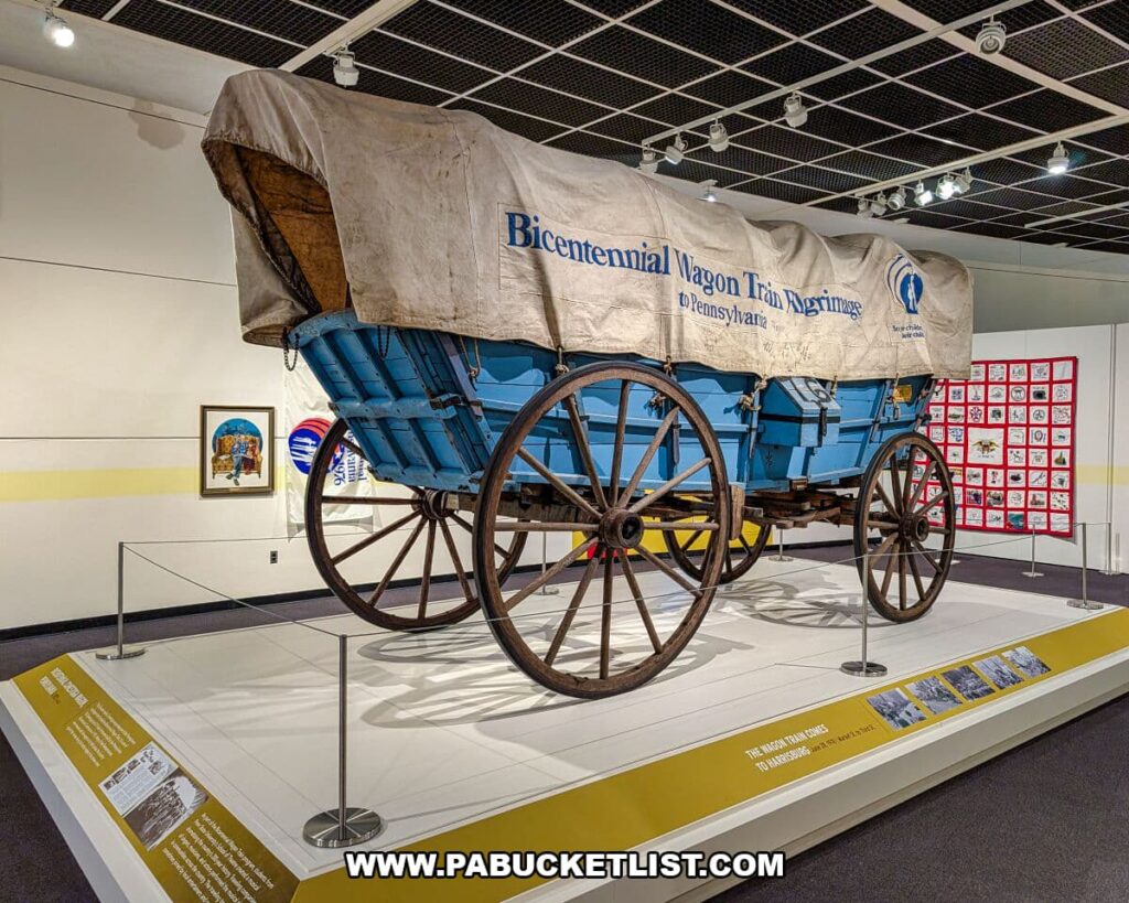 Historic blue-covered wagon displayed at The State Museum of Pennsylvania in Harrisburg, labeled as part of the Bicentennial Wagon Pilgrimage, illustrating how Pennsylvanians commemorated America’s 200th anniversary and reflected on the nation’s Revolutionary-era roots