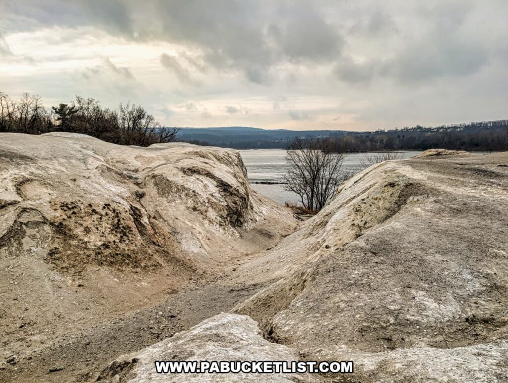 Shallow ravine cutting through the chalky quarry mounds at the White Cliffs of Conoy, opening toward views of the Susquehanna River under an overcast sky in Lancaster County, Pennsylvania.