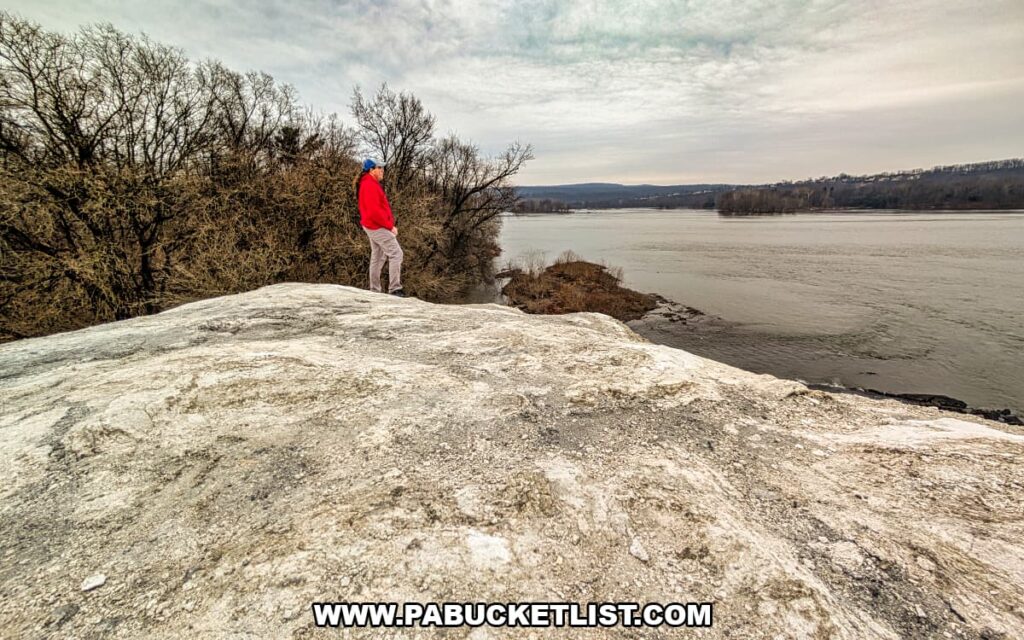Visitor standing atop the chalky quarry surface at the White Cliffs of Conoy, looking out over the Susquehanna River and wooded shoreline in Lancaster County, Pennsylvania.