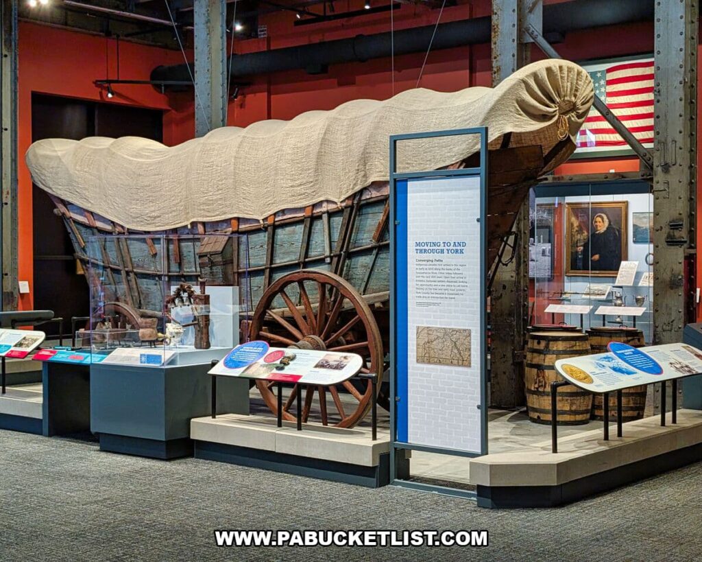 Large covered wagon exhibit at the York County History Center illustrating migration and settlement in York County, accompanied by interpretive panels and artifacts that tell the story of people moving to and through the region.