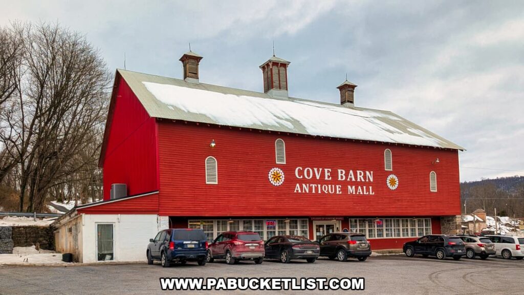 Exterior view of Cove Barn Antiques in Duncannon, Pennsylvania, showing the large red repurposed barn with antique mall signage, rooftop cupolas, and parked cars in front