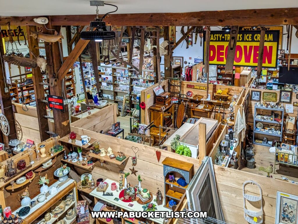 Overhead view inside Cove Barn Antiques in Duncannon, Pennsylvania, showing rows of vendor booths filled with vintage decor, collectibles, furniture, and hanging farm tools beneath exposed barn beams