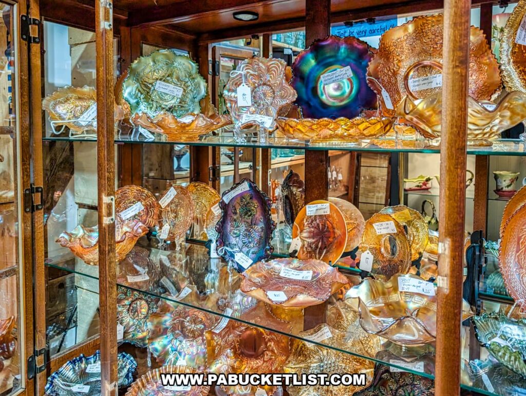 Glass display cabinet inside Cove Barn Antiques in Duncannon, Pennsylvania, filled with colorful vintage carnival glass bowls, plates, and decorative pieces arranged on shelves