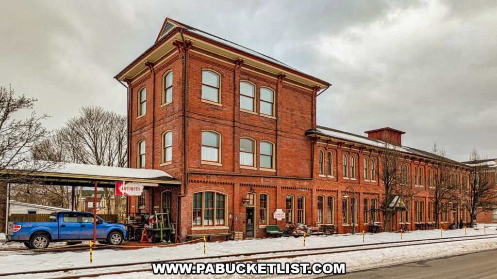 Exterior view of Sunbury Station Antiques in Northumberland County, Pennsylvania, showing the long red-brick historic train station building with arched windows and a covered platform along a snow-dusted street.