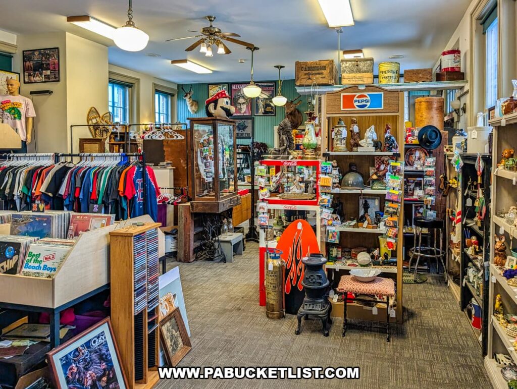 First-floor vendor booths at Sunbury Station Antiques in Northumberland County, Pennsylvania, featuring racks of vintage clothing, vinyl records, glass display cases, advertising signs, small collectibles, and nostalgic memorabilia inside the historic train station building.