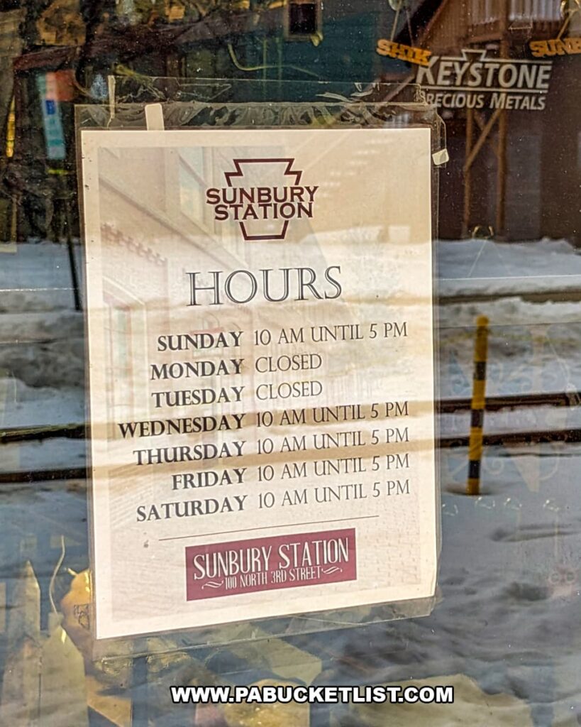 Store hours sign posted in the window at Sunbury Station Antiques in Northumberland County, Pennsylvania, listing weekly opening times for the multi-vendor antique shop inside the historic train station.