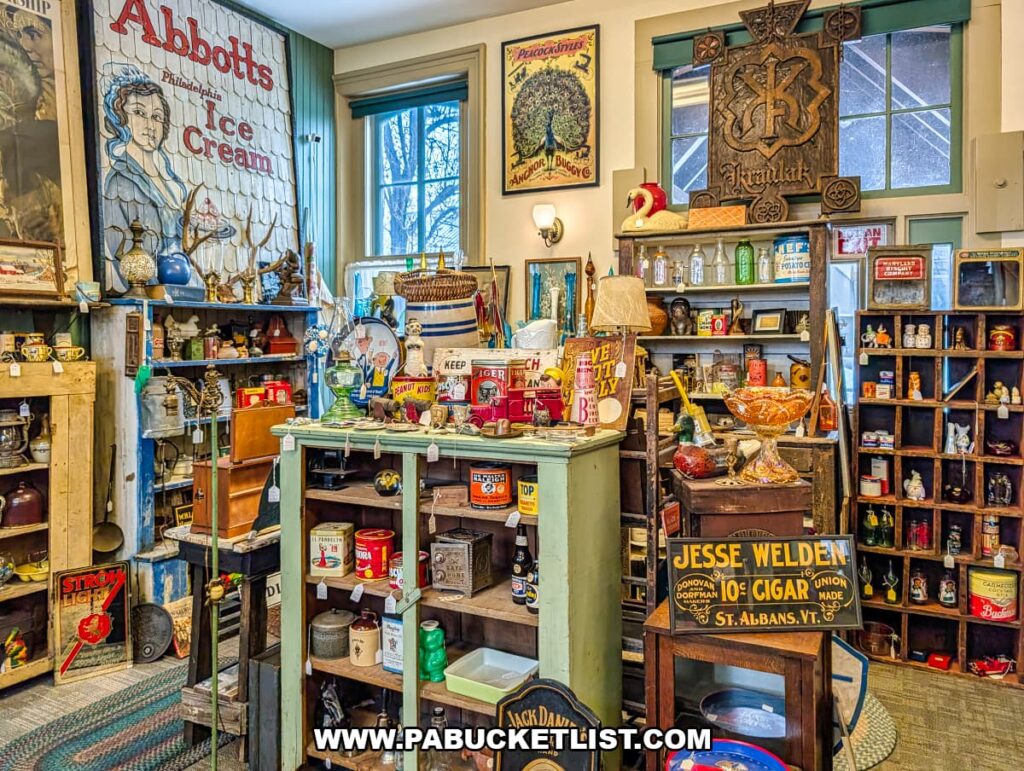 Vendor booth at Sunbury Station Antiques in Northumberland County, Pennsylvania, filled with vintage advertising signs, antique bottles and tins, glassware, small collectibles, and retro decor displayed inside the historic train station building.