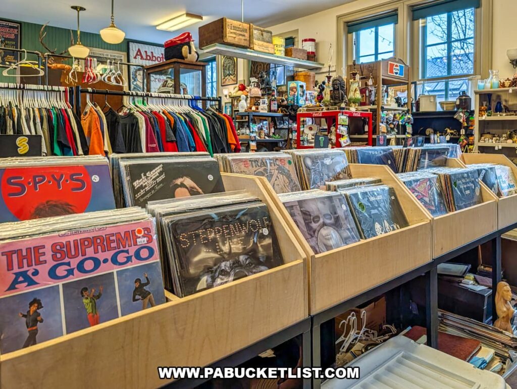 Bins of vintage vinyl records and album covers displayed inside Sunbury Station Antiques in Northumberland County, Pennsylvania, with racks of retro clothing and assorted collectibles visible throughout the historic train station building.