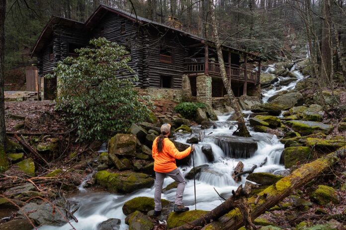 Exploring-Bordner-Cabin-selfie-Swatara-State-Park Hiker standing beside cascading water along Rattling Run at Acrigg’s Falls with Bordner Cabin overlooking the stream in Swatara State Park, Lebanon County, Pennsylvania.