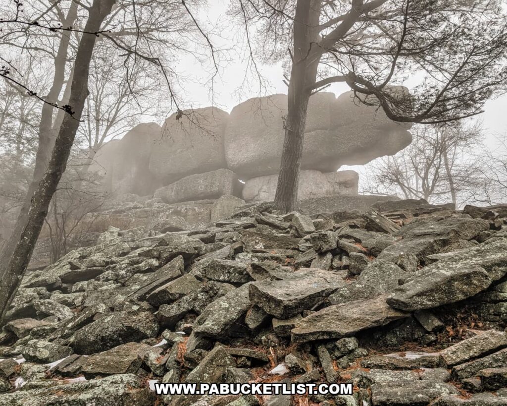 Massive stacked conglomerate boulders forming the Boxcar Rocks outcropping on State Game Lands 211 in Lebanon County, Pennsylvania, rising above a rocky slope in a foggy forest.