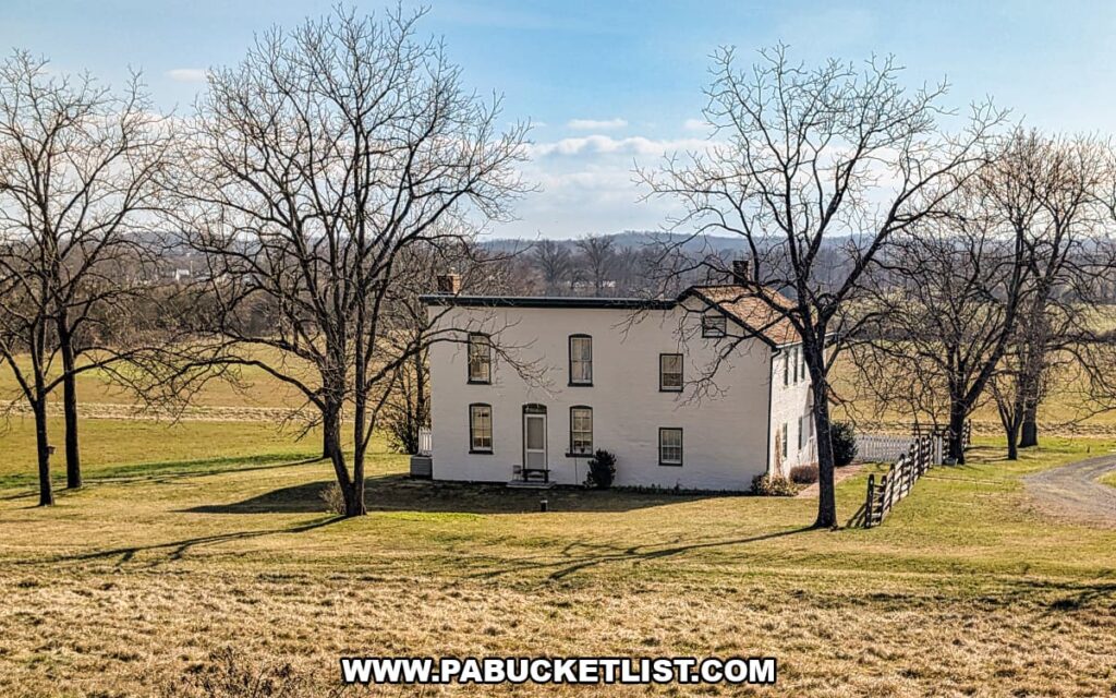 Historic white farmhouse surrounded by open fields and bare trees on the Gettysburg Battlefield viewed from a Gettysburg Railway sightseeing train excursion in Gettysburg, Pennsylvania.
