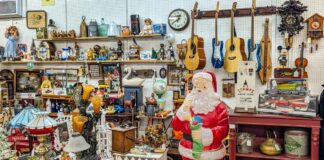 Vendor booth filled with vintage collectibles, guitars, lamps, toys, and a large Santa Claus figure at Fayetteville Antique & Craft Mall in Franklin County, Pennsylvania.