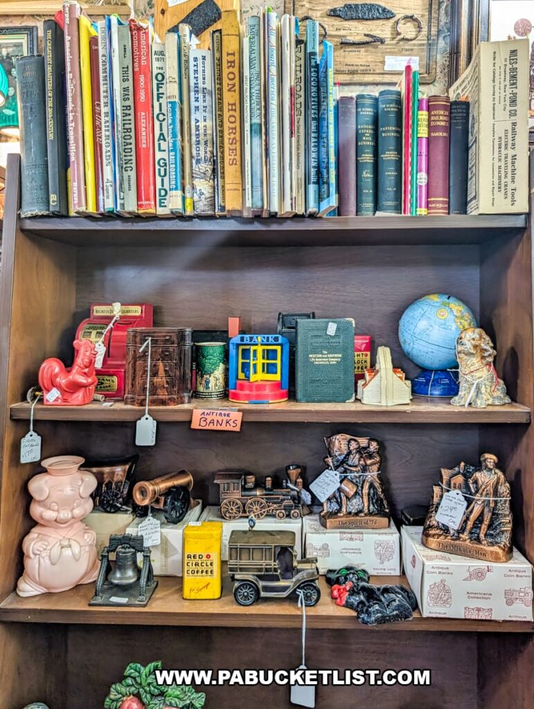 Shelf display of antique coin banks, vintage books, and collectible figurines inside Wagon Wheel Antiques in Butler County, Pennsylvania.