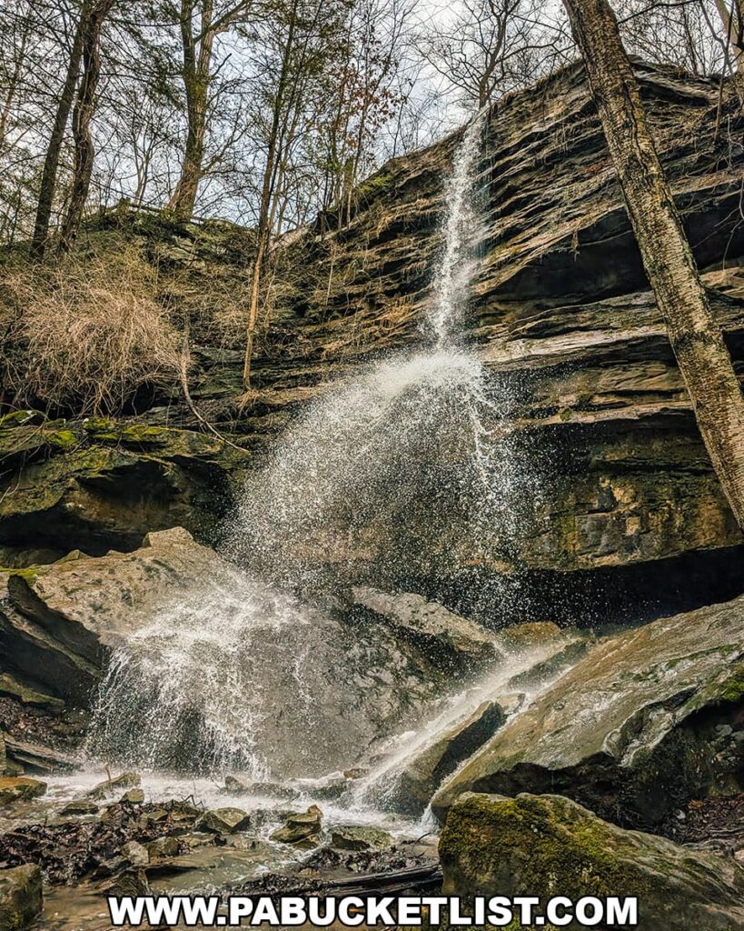 Front view of Alpha Falls dropping from a tall sandstone cliff into a rocky gorge at McConnells Mill State Park in Lawrence County, Pennsylvania.