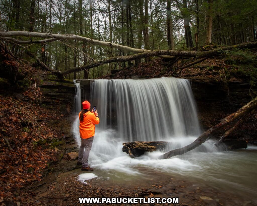 Photographer standing beside Grindstone Falls capturing images of the waterfall along an unnamed tributary of Grindstone Run at McConnells Mill State Park in Lawrence County, Pennsylvania.
