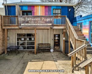 Exterior view of In Between Pages Bookstore in York PA showing colorful mural facade, wooden staircase, and entrance to the two-floor shop selling used books records CDs DVDs and comics