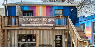 Exterior view of In Between Pages Bookstore in York PA showing colorful mural facade, wooden staircase, and entrance to the two-floor shop selling used books records CDs DVDs and comics