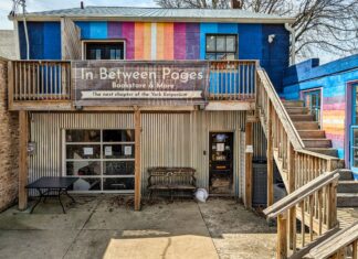 Exterior view of In Between Pages Bookstore in York PA showing colorful mural facade, wooden staircase, and entrance to the two-floor shop selling used books records CDs DVDs and comics