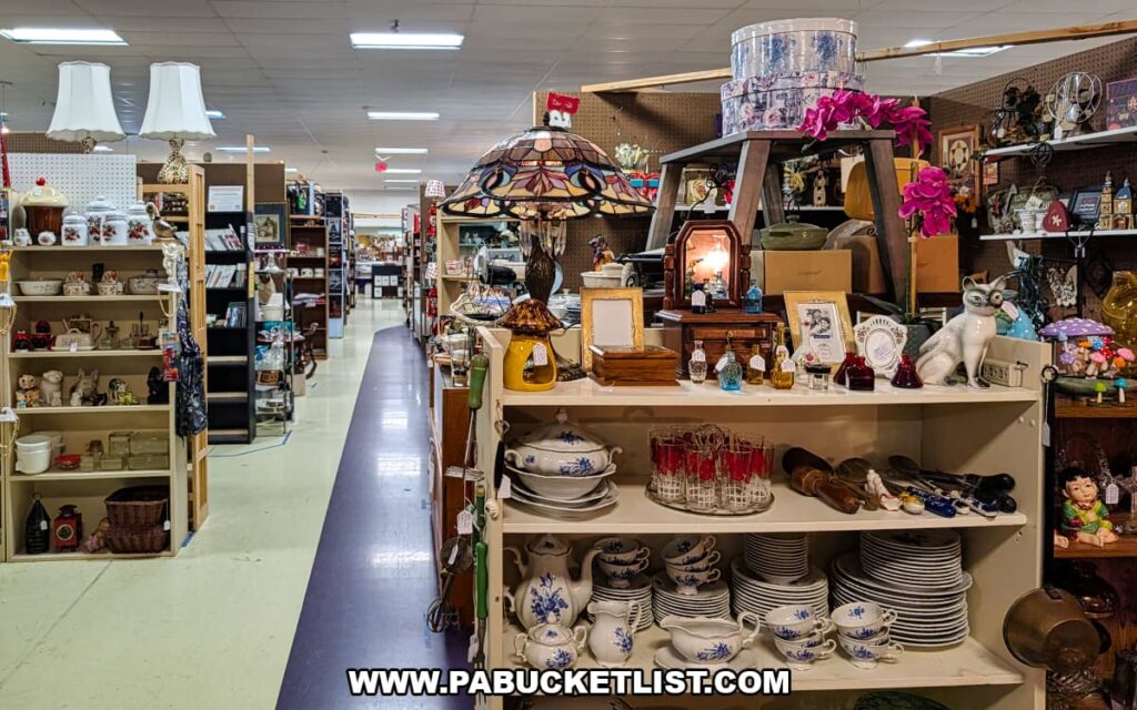 Aisle lined with vendor booths displaying antiques collectibles lamps glassware and vintage decor inside Pen-Mar Antique Market in Waynesboro Pennsylvania