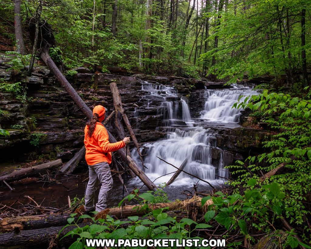 Hiker standing beside Jarrett Falls as the waterfall cascades over layered rock ledges on Roaring Run in Fulton County, Pennsylvania