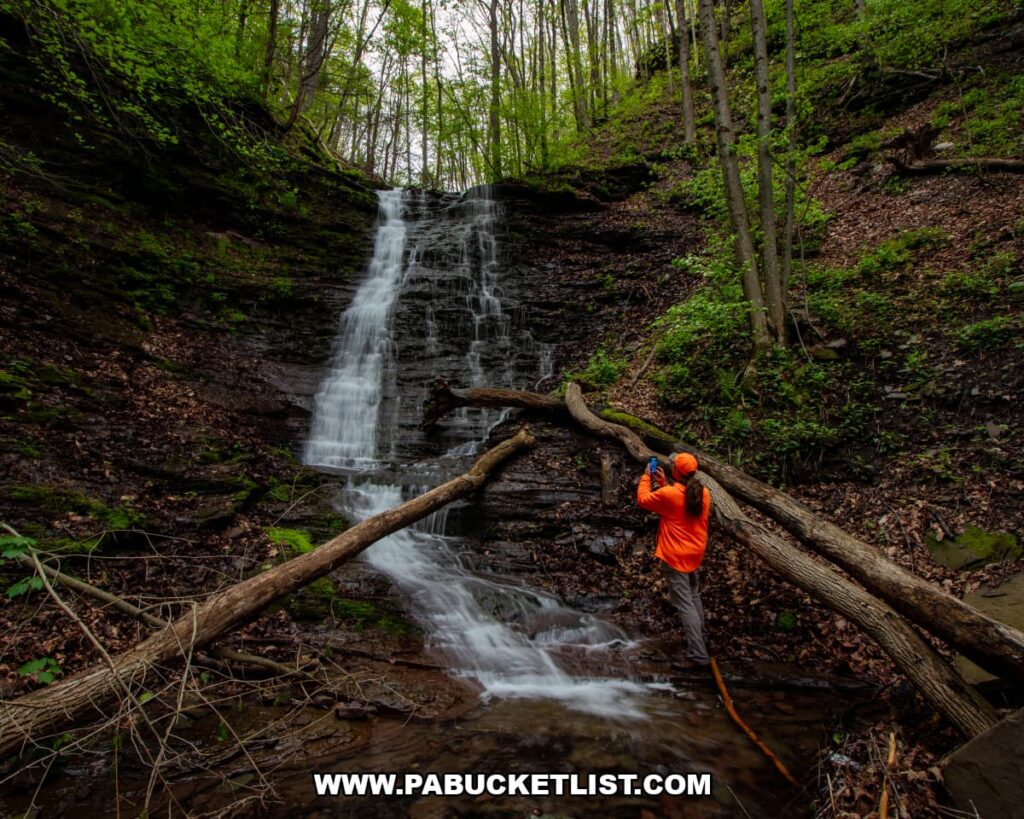 Wide view of Rail Island Run Falls with a photographer standing at the base of the waterfall in Tioga County, Pennsylvania.