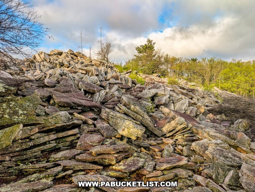 layered rock outcrop at waggoners gap hawk watch in perry county pennsylvania with spring foliage and partly cloudy sky above